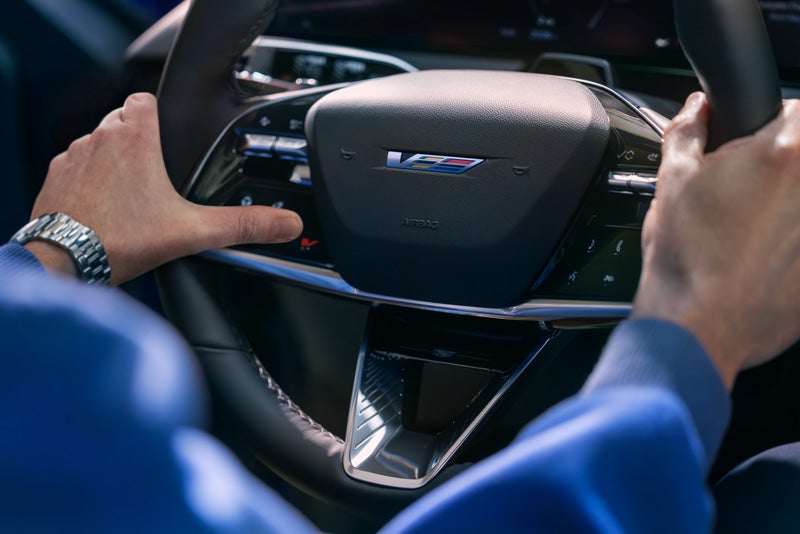Close-up of a Man About to Press the V-Button on the 2026 OPTIQ-V Steering Wheel | King Cadillac in FLORENCE SC